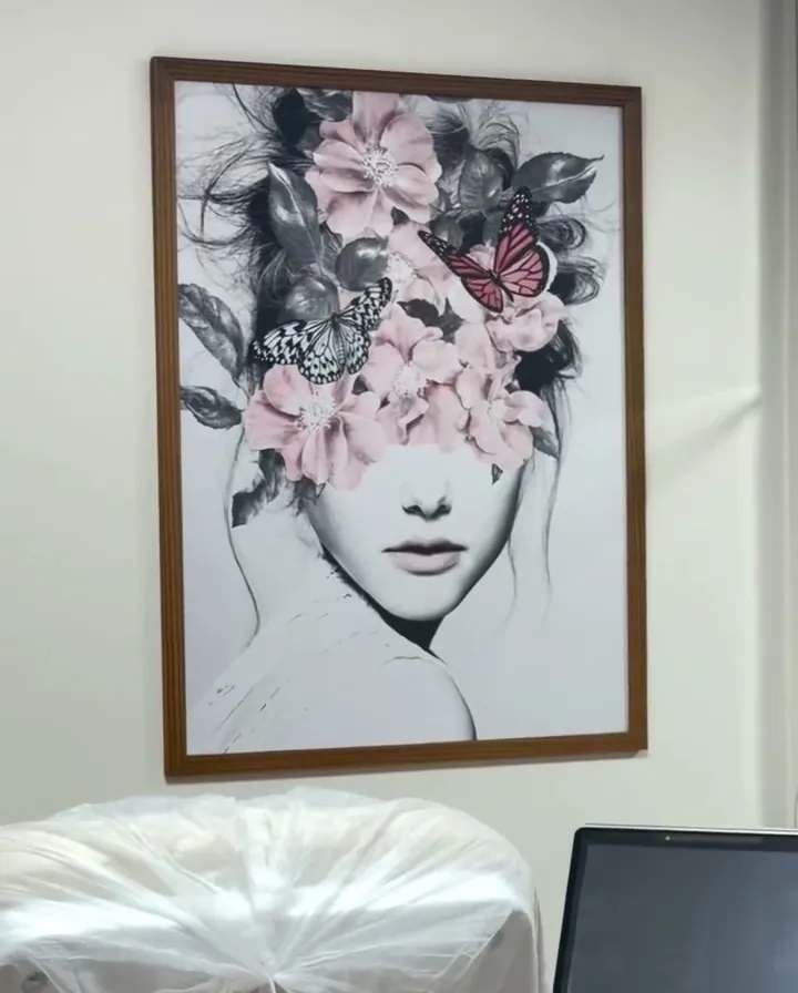 Sala de procedimentos com quadro de mulher e flores e equipamento de estética