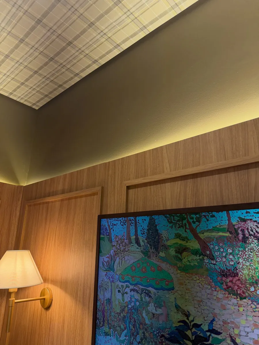 Sala com painel de madeira, luminária e quadro colorido